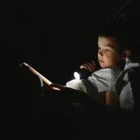 Menino lendo no escuro